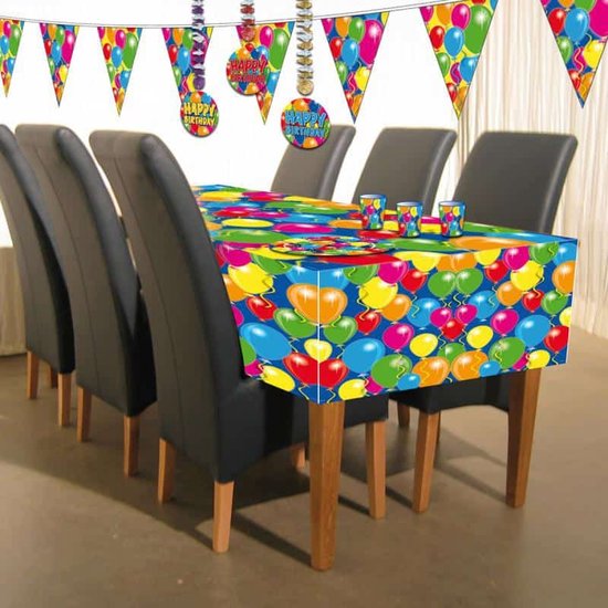 Gedekte tafel met blauw tafelkleed met ballonnen, bekers en verjaardagsdecoraties.