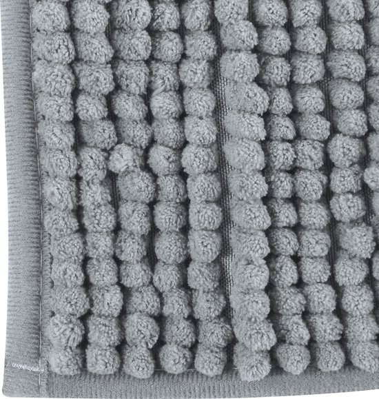 Gedetailleerde close-up van de grijze badmat met ronde, pluizige ribbels.