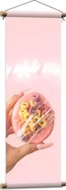 Textielposter - Roze Donut in Hand - 30x90 cm Foto op Textiel