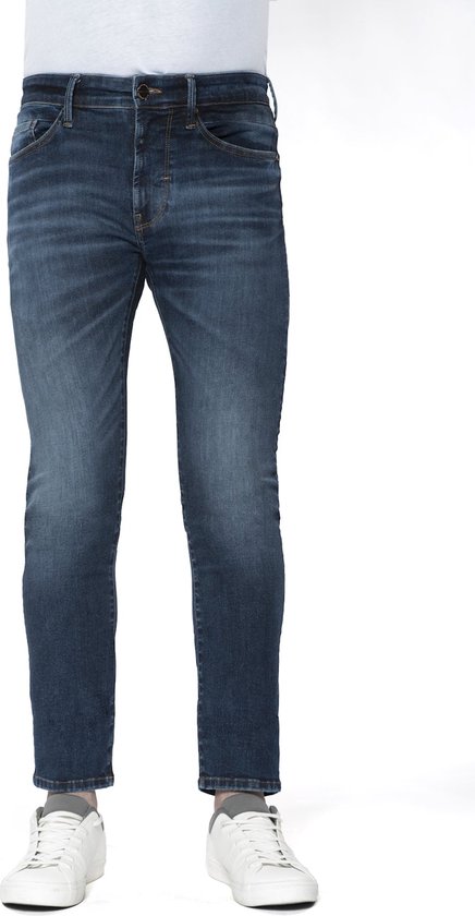 Donkerblauwe slim-fit herenjeans met subtiele vervaagde accenten, gecombineerd met witte sneakers.