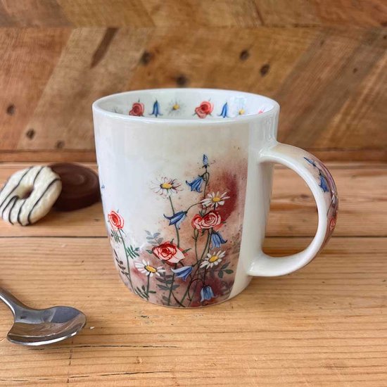 Witte mok met aquarelprint van rode rozen, witte madeliefjes en blauwe klokjesbloemen. De print loopt door op de oor.