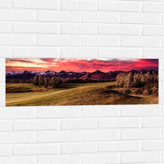 Muursticker - Roze Wolken boven Landschap Vol Bomen en Bergen - 90x30 cm Foto op Muursticker