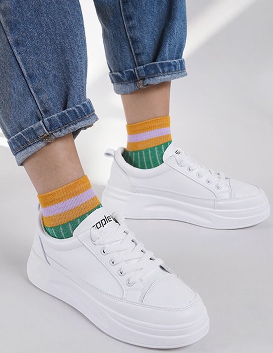 Witte sneakers met streepjes kousen in geel, paars en groen.