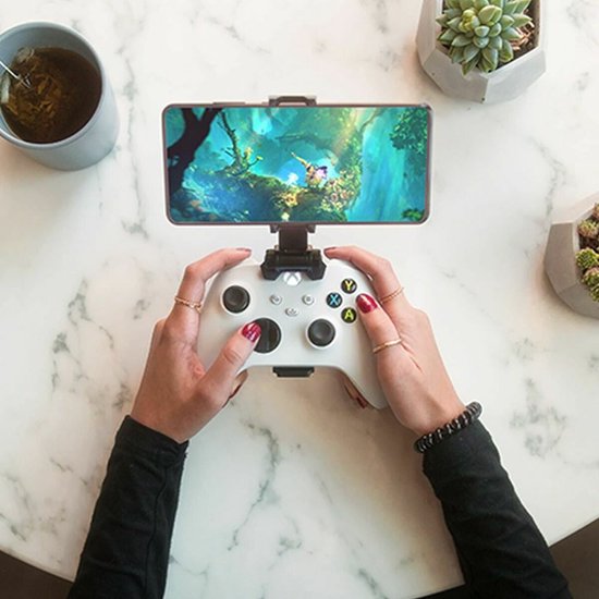Vrouw met rode nagellak houdt een witte Xbox controller met telefoon vast.