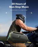 Man op motor met groene speaker met band, rijdt overdag.