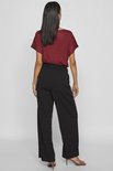 Model van achteren in bordeauxrode top en wijde zwarte broek met hoge taille.
