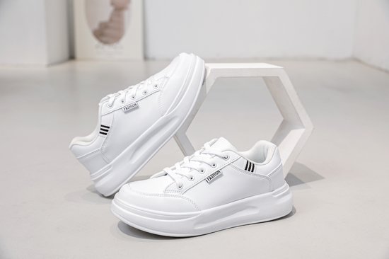 Witte lage sneakers met veters, op een decoratieve standaard.