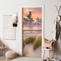 Deursticker met zonsondergang, strand en duingras, in een gang.