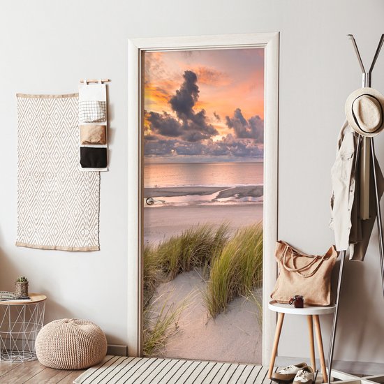 Deursticker met zonsondergang, strand en duingras, in een gang.