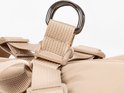 Dichtbijdetail van een metalen D-ring en beige bandjes van een hondenharnas.