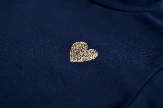 Gros plan d'un cœur brodé doré sur un tissu bleu marine.