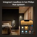 Een slaapkamer met sfeervolle verlichting, bediend via een smartphone met de Philips Hue app. De tekst zegt 'Integreert naadloos in het Philips Hue-systeem'.