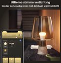 Een stijlvolle lamp met een amberkleurige kap en een betonnen voet, verlicht met warmwit licht.