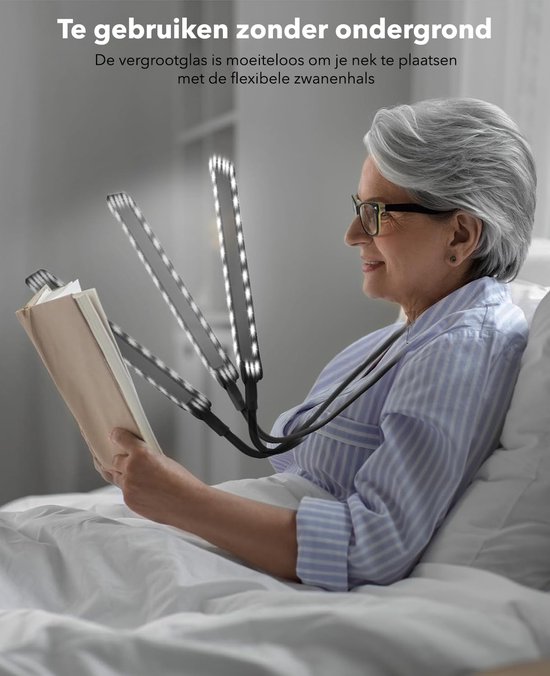 Een vrouw met bril leest een boek in bed, vergrootglas met flexibele zwanenhals om de nek.