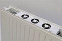 Witte radiator ventilator met drie zwarte ventilatoren, gemonteerd in een witte radiator.