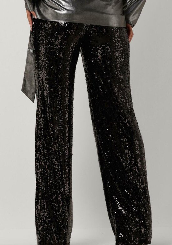 Dichtbij shot van het model dat een broek met zwarte pailletten en een zilverkleurig jasje draagt.