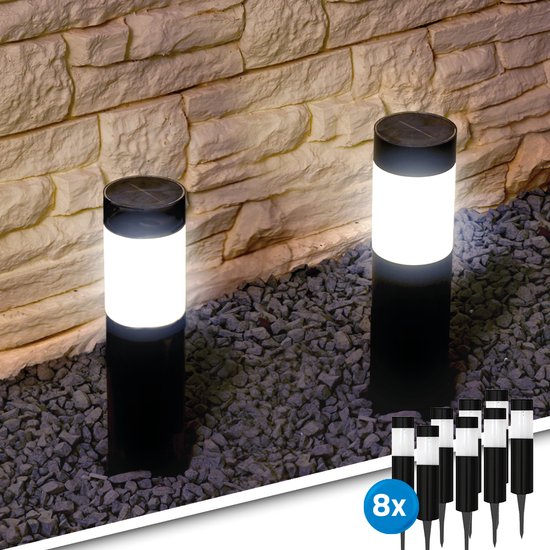 Twee zwarte tuinlampen met witte, verlichte kappen staan op een ondergrond van grijze steentjes.