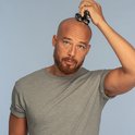 Man met stoppels en baard scheert zijn hoofd met een zwart Remington scheerapparaat met 5 scheerkoppen.