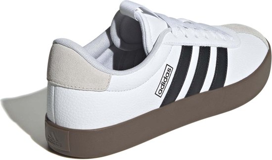 Achterkant van witte Adidas sneakers met zwarte strepen en bruine zool.