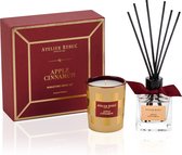 Een Atelier Rebul 'Apple Cinnamon' Mini Home Kit met een rood doosje, een gouden geurkaars en een glazen geurstokjeshouder met zwarte stokjes.