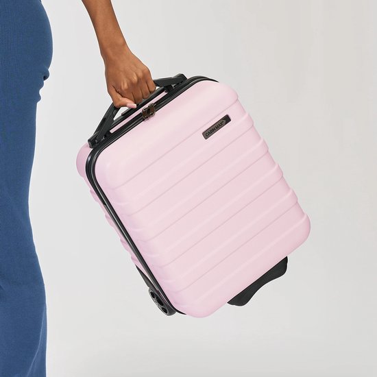 Een hand wordt gebruikt om de lichtroze Cabin Max handbagage koffer vast te houden.