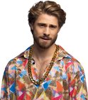 Man met gekruiste armen draagt een kleurrijk, geometrisch bedrukt shirt en een dikke gouden ketting.