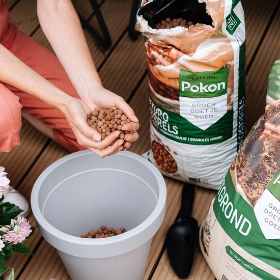 Vrouw vult plantenbak met Pokon Hydrokorrels. Naast zak met korrels en potgrond.
