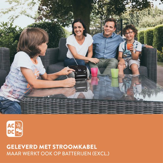 Gezin op een loungeset in de tuin, met een Lenco radio CD-speler op de salontafel. De jongen links bedient het apparaat.