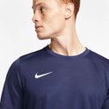 Close-up van een man met rood haar in een donkerblauw Nike sportshirt met wit logo op de borst.