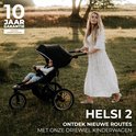 Vrouw met lang blond haar in een zomerjurk duwt een zwarte driewielkinderwagen met baby in een zonnige weide.