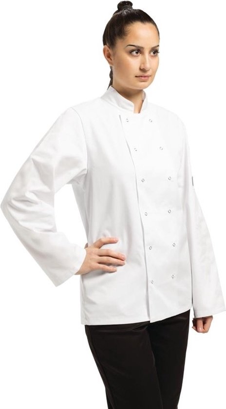 Vrouw in witte koksbuis met lange mouwen en zwarte broek, hand op de heup.