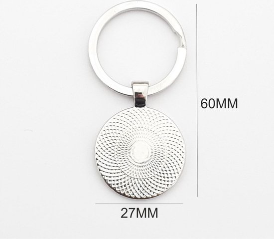 Porte-clés argenté avec un pendentif rond de 27mm de large et 60mm de haut. Le pendentif présente un motif circulaire détaillé.