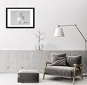 Moderne woonkamer met een zwarte A2 fotolijst aan de muur, naast een grijze fauteuil.