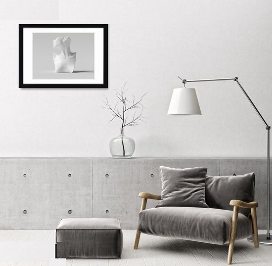 Moderne woonkamer met een zwarte A2 fotolijst aan de muur, naast een grijze fauteuil.