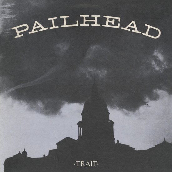 Pailhead - Trait albumhoes met een donkere, dreigende lucht boven een silhouet van een gebouw.