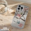 Smartphone met een doorzichtige hoes met Japanse bloemenprint, naast een glas water.