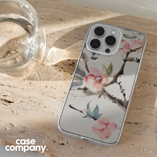 Smartphone met een doorzichtige hoes met Japanse bloemenprint, naast een glas water.