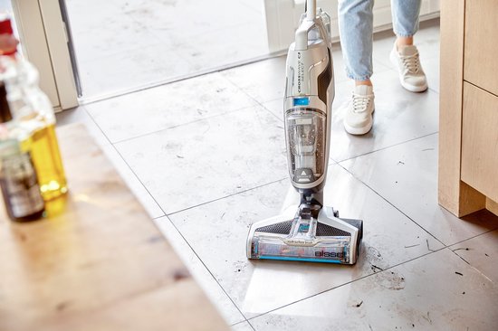 BISSELL Crosswave C3 Select stofzuiger met dweil reinigt vuile tegelvloer, met keukenmeubels op de achtergrond.