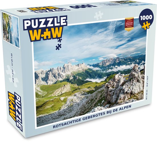 Boîte de puzzle de 1000 pièces représentant un paysage de montagnes rocheuses dans les Alpes sous un ciel bleu avec des nuages.