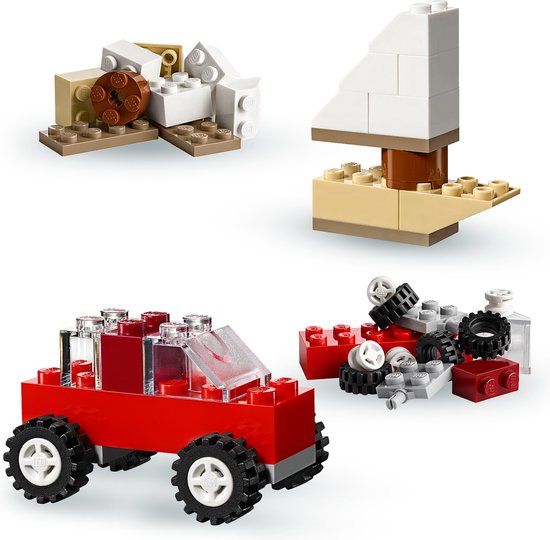 LEGO-modellen: rode auto met grote wielen, zandkleurige en witte stenen, en een witte zeilboot met zandkleurige basis.