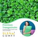 Vrouw met groen ergonomisch kussen, omringd door muntbladeren. De tekst "Premium Traagschuim" staat op de afbeelding.