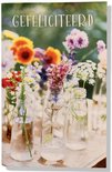 Kaart met diverse bloemen in glazen vaasjes. Tekst: GEFELICITEERD.