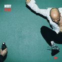 Moby Play albumhoes met Moby die in de lucht springt, in een witte blouse en zwarte broek.