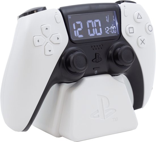 Witte en zwarte PlayStation 5-controller wekker op een oplaadstation, met een digitaal display dat 12:00 aangeeft.