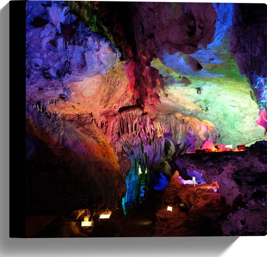 Een grot verlicht met veelkleurige lampen. Stalactieten en stalagmieten in paars, rood, groen en blauw.
