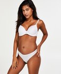 Model in witte beha en slip, van voren bekeken, met de hand op de heup.
