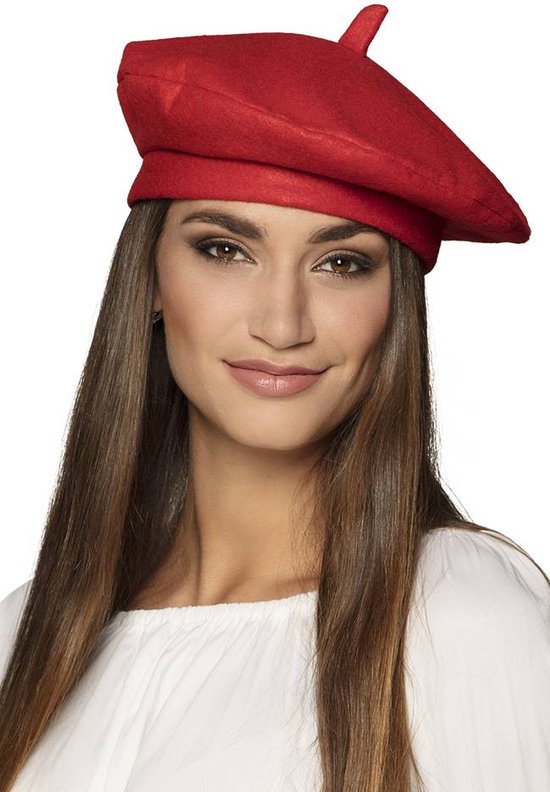 Een vrouw met lang bruin haar draagt een felrode baret boven een witte top.