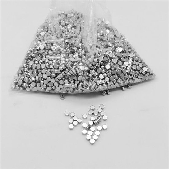 Een grote doorzichtige plastic zak gevuld met honderden kleine, cilindervormige zilverkleurige magneten. Enkele magneten liggen los rond de zak.