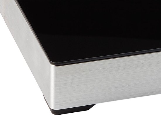 Détail du coin d'une plaque de cuisson à induction avec une surface noire brillante et un cadre en métal brossé.