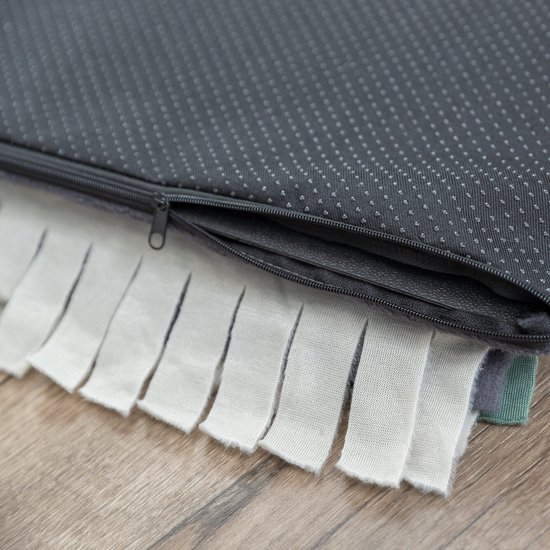 Donkergrijze achterkant van een snuffelmat met anti-slip noppen en rits. Rand met witte en lichtgroene stroken.